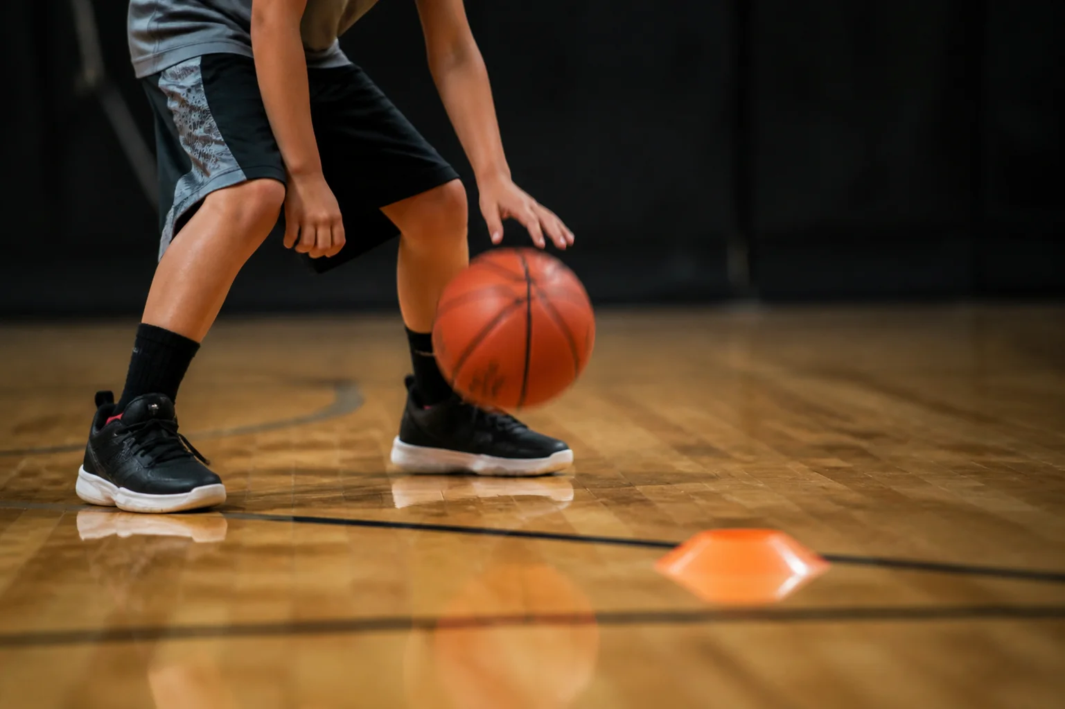 Close view of a child controlling a basketball near a floor marker